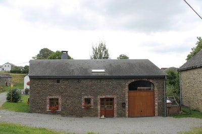 De natuurstenen schuur met de garagepoorten.